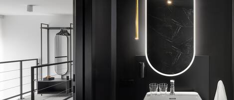 A modern bathroom with a large mirror, a white sink, and a towel rack.