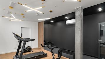 Ein modernes Fitnessstudio mit Trainingsgeräten, Holzboden und Schwarz-Weiß-Design.