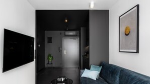 Una sala moderna con un televisor de pantalla plana, un sofá azul oscuro con cojines, una mesa de centro y una obra de arte abstracta enmarcada en la pared.