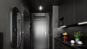 Una cocina moderna con microondas, estufa y una pequeña encimera con una planta en maceta y tazas.