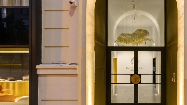 Entrada de hotel con puerta de vidrio, arco y cámara de seguridad.