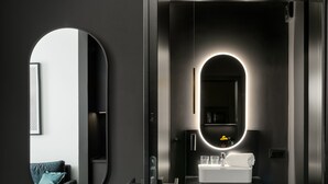 Un baño moderno con un espejo redondo, un lavabo con una toalla y un cuadro en la pared.