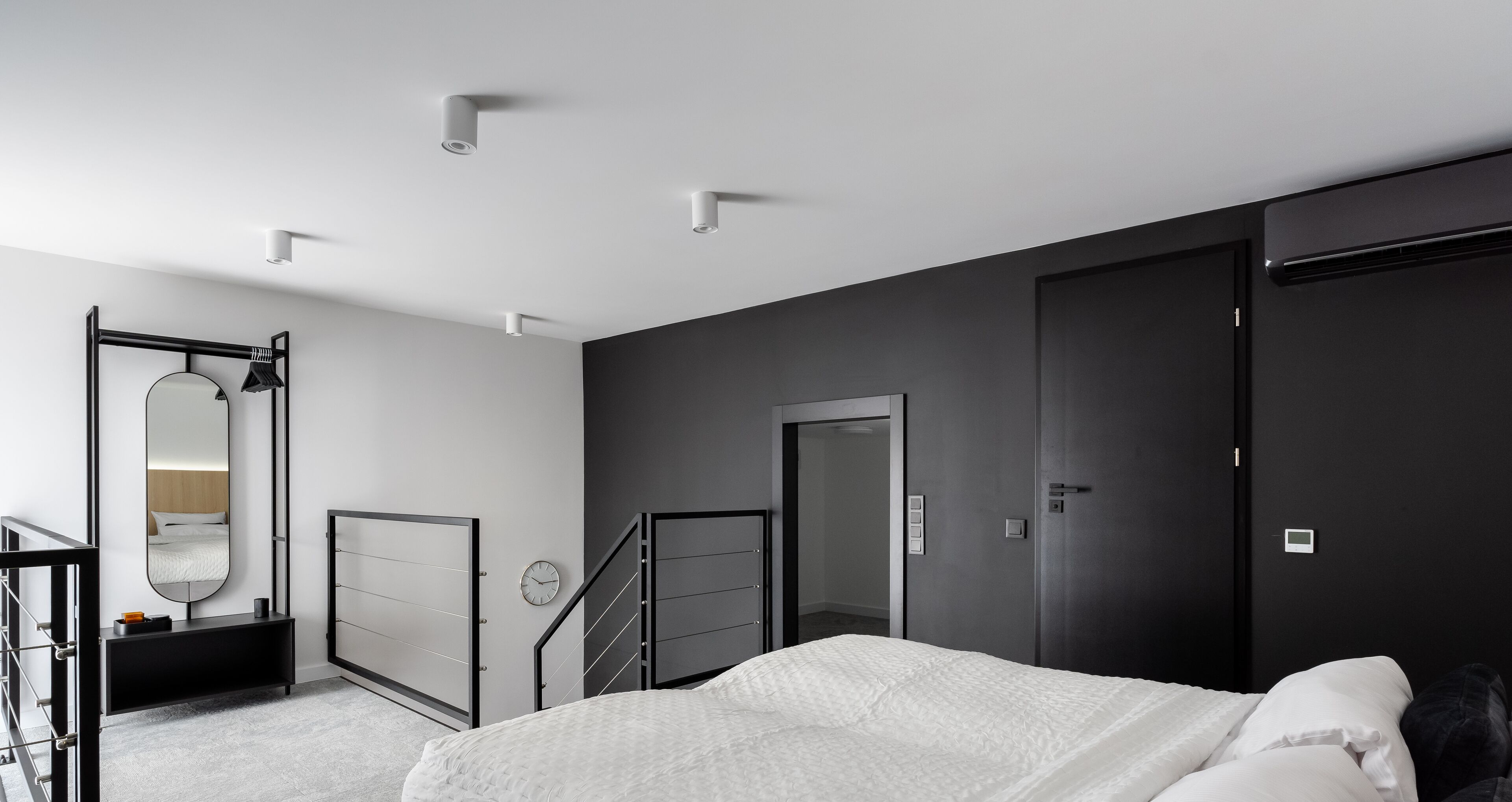 Una camera da letto moderna con un letto, uno specchio grande, un armadio e una scrivania con una sedia.