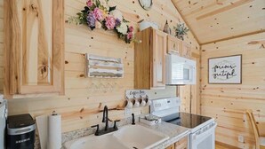 Eine Holzhütte mit einer Küche, inklusive Spüle, Kaffeemaschine und Mikrowelle.