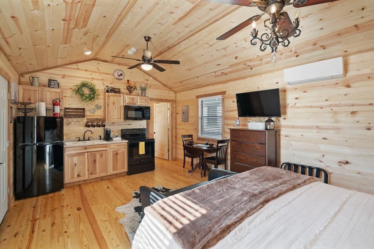 A cozy cabin interior with a kitchen, dining area, and a bed.