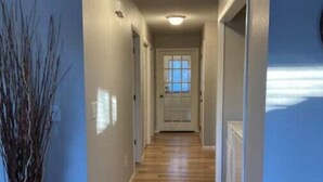 A hallway with wooden flooring, a potted plant, and a door at the end. - Riverfront Twin Home
 (La Crosse)