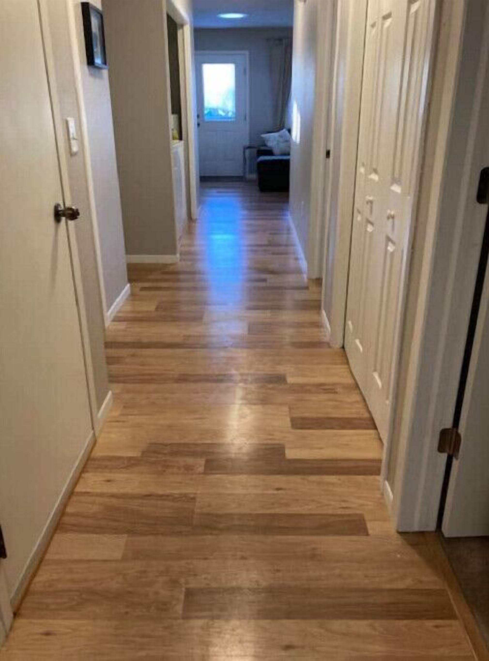 A hallway with wooden flooring and white doors.