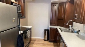 A kitchen with wooden cabinets, a stainless steel refrigerator, a microwave, and a sink. - Riverfront Twin Home
 (La Crosse)