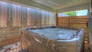 A hot tub under a covered area with wooden walls and a wooden fence. - Wanderlust #1 Hot Tub Shared Outdoor Space (Fredericksburg)