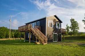Une maison en bois à deux étages, dotée d’une terrasse et d’un escalier.
