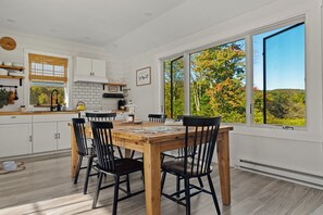 Une cuisine moderne avec des meubles blancs, une table à manger en bois et des chaises noires.