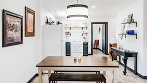 A modern kitchen with a central island, a dining table with a bench, and a chandelier. - Faulkner Ranch Bunkhouse (Llano)