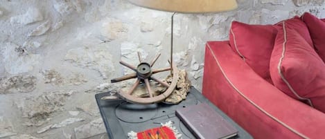 Un rincón acogedor con una lámpara de estilo vintage, un cojín rojo y una mesita con un libro y un objeto decorativo.