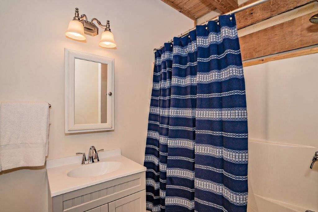 A bathroom with a white sink, a mirror, and a blue patterned shower curtain.