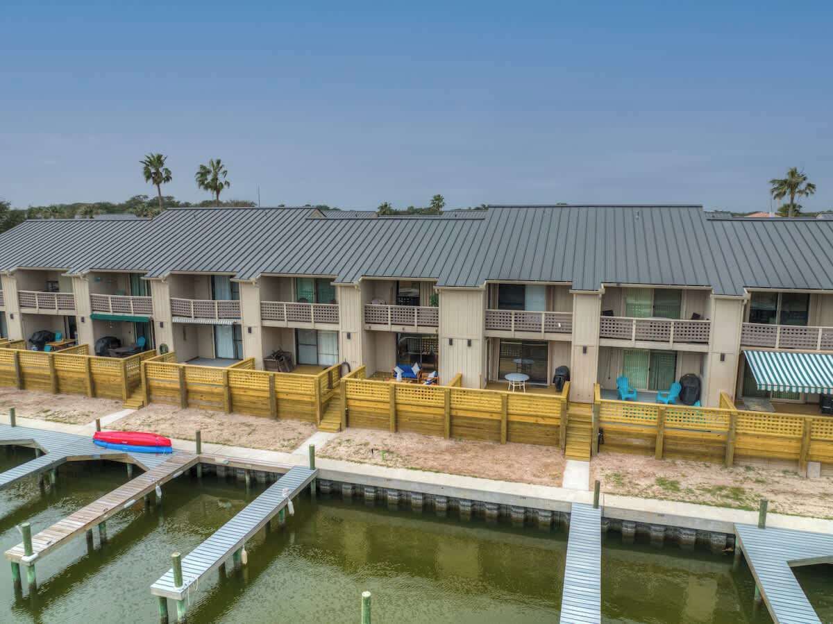 A beachfront hotel with multiple balconies, a pool area, and a dock.