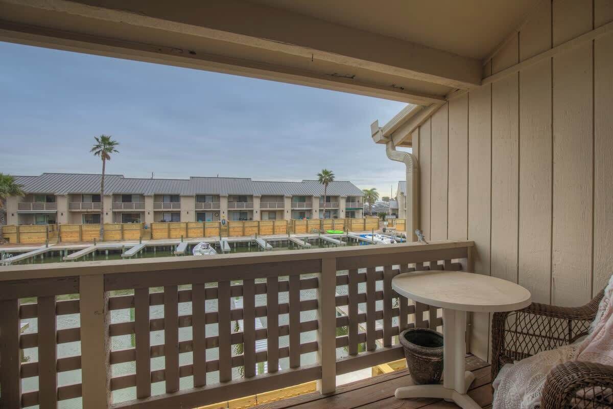 Un balcone con vista su un edificio di un hotel, un tavolino e una sedia in vimini.
