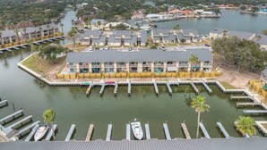 Un hôtel situé au bord de l’eau, avec plusieurs bateaux amarrés, un port de plaisance et un grand bâtiment doté de balcons.