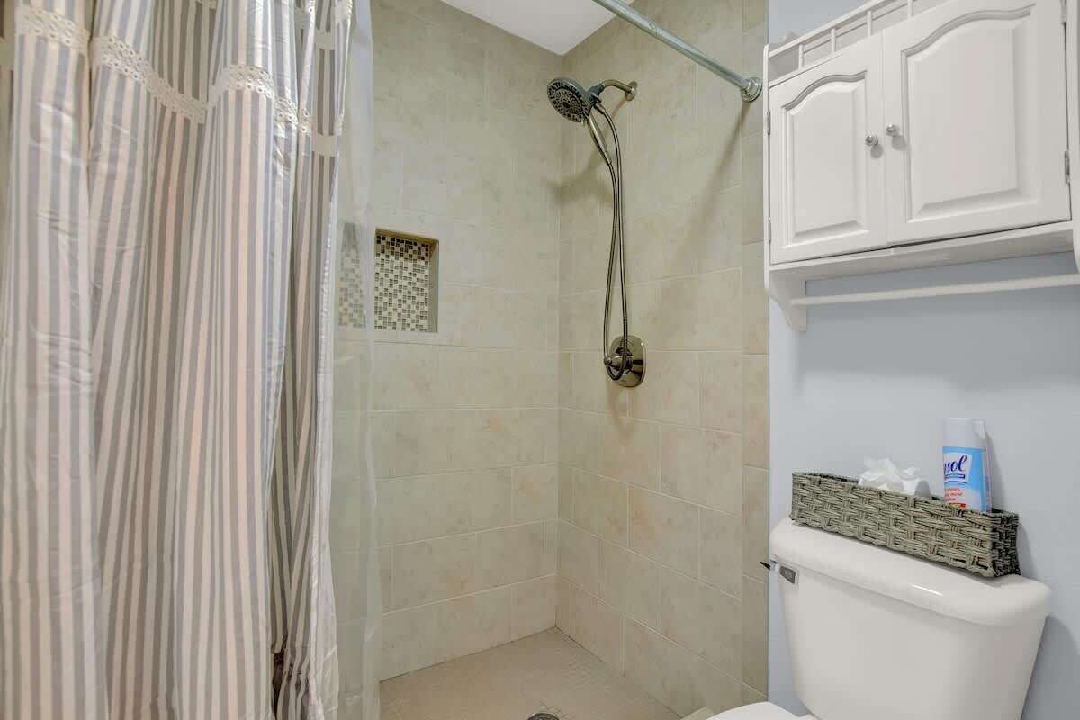 A bathroom with a shower, toilet, and a cabinet with toiletries.