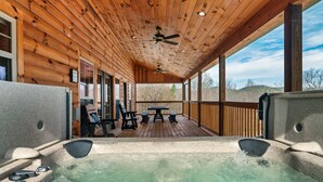 Eine Holzterrasse mit Whirlpool, Sitzgelegenheiten und Deckenventilator.