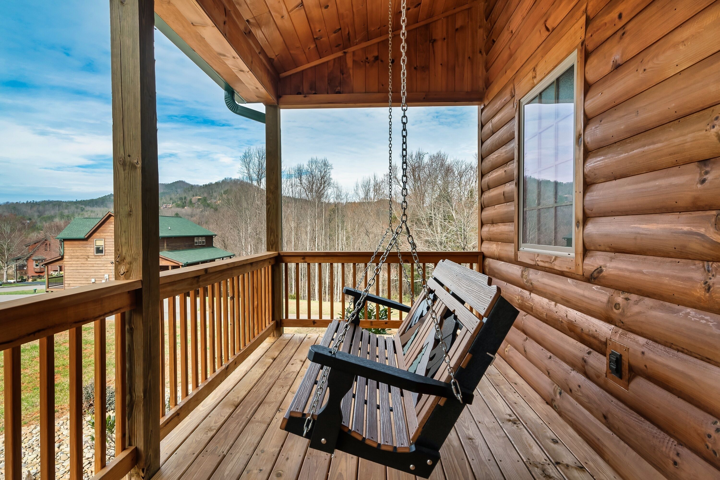 A wooden cabin with a porch, a swing, and a view of the surrounding landscape.