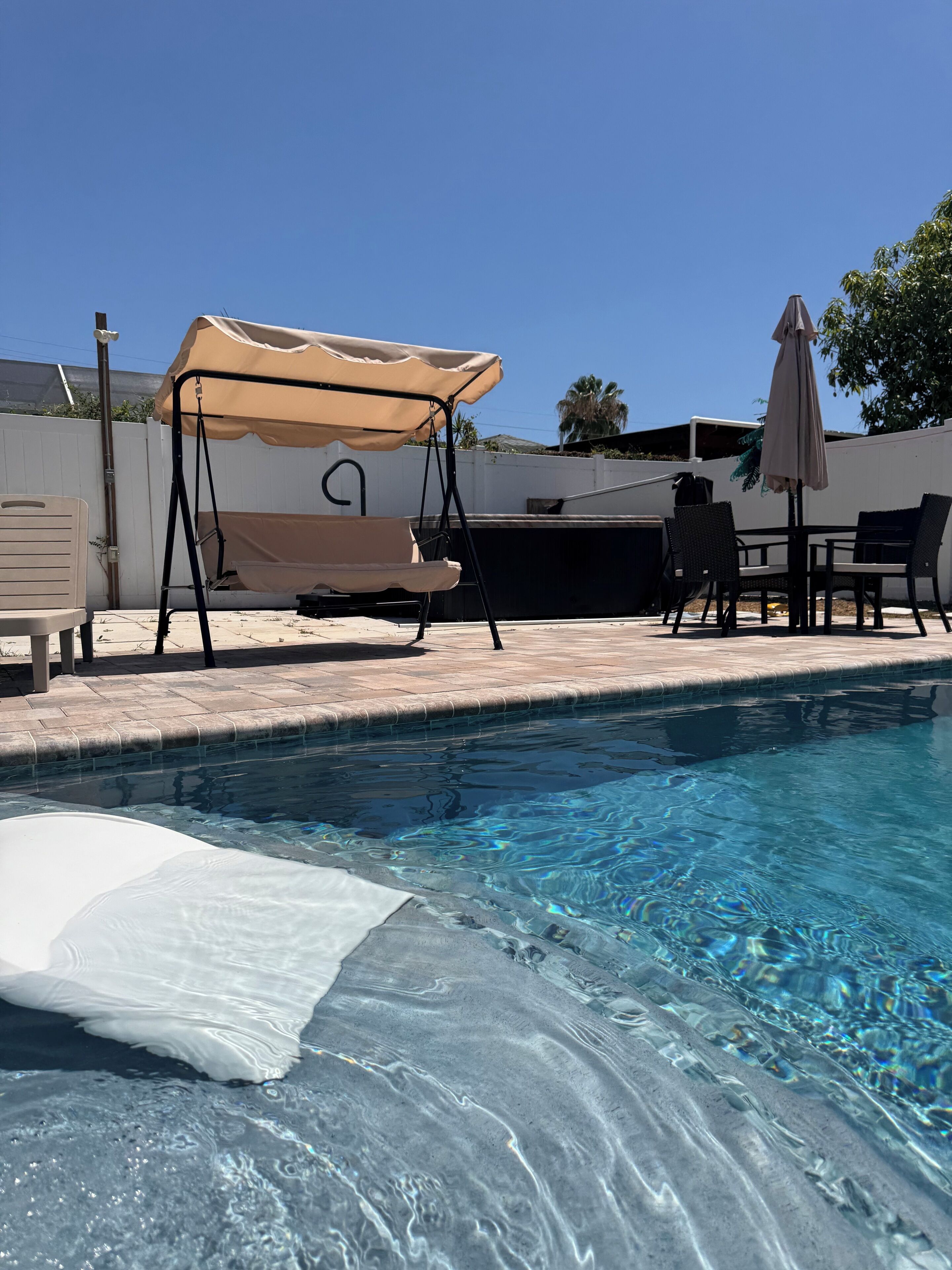 Piscina com cadeira de balanço e área de estar coberta.