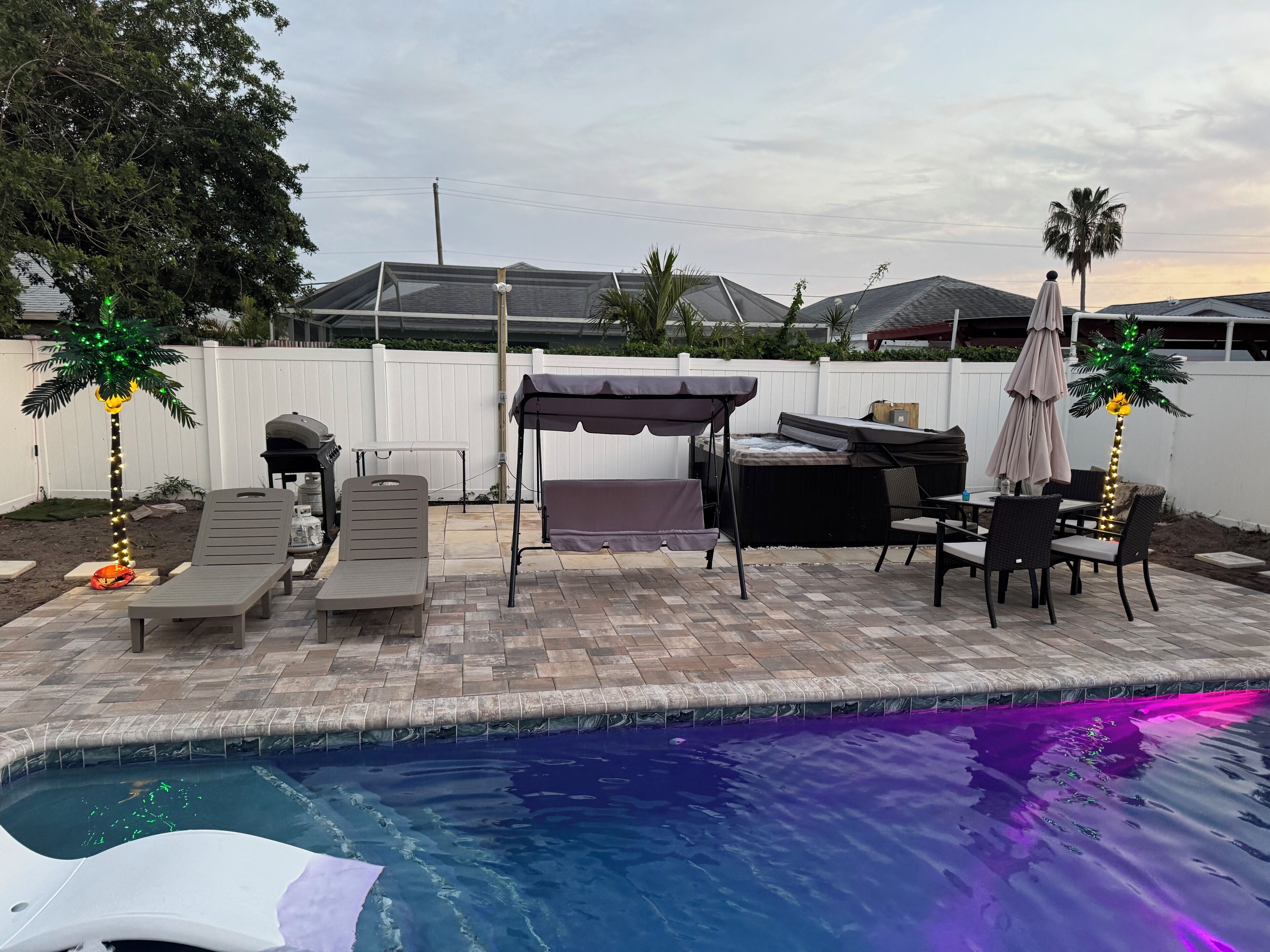 A backyard with a swimming pool, outdoor furniture, a hot tub, and a pergola.