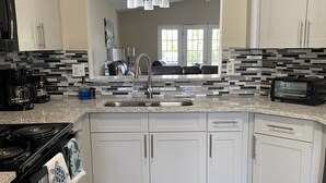 Una cocina moderna con armarios blancos, encimera de granito, horno empotrado y lavavajillas.