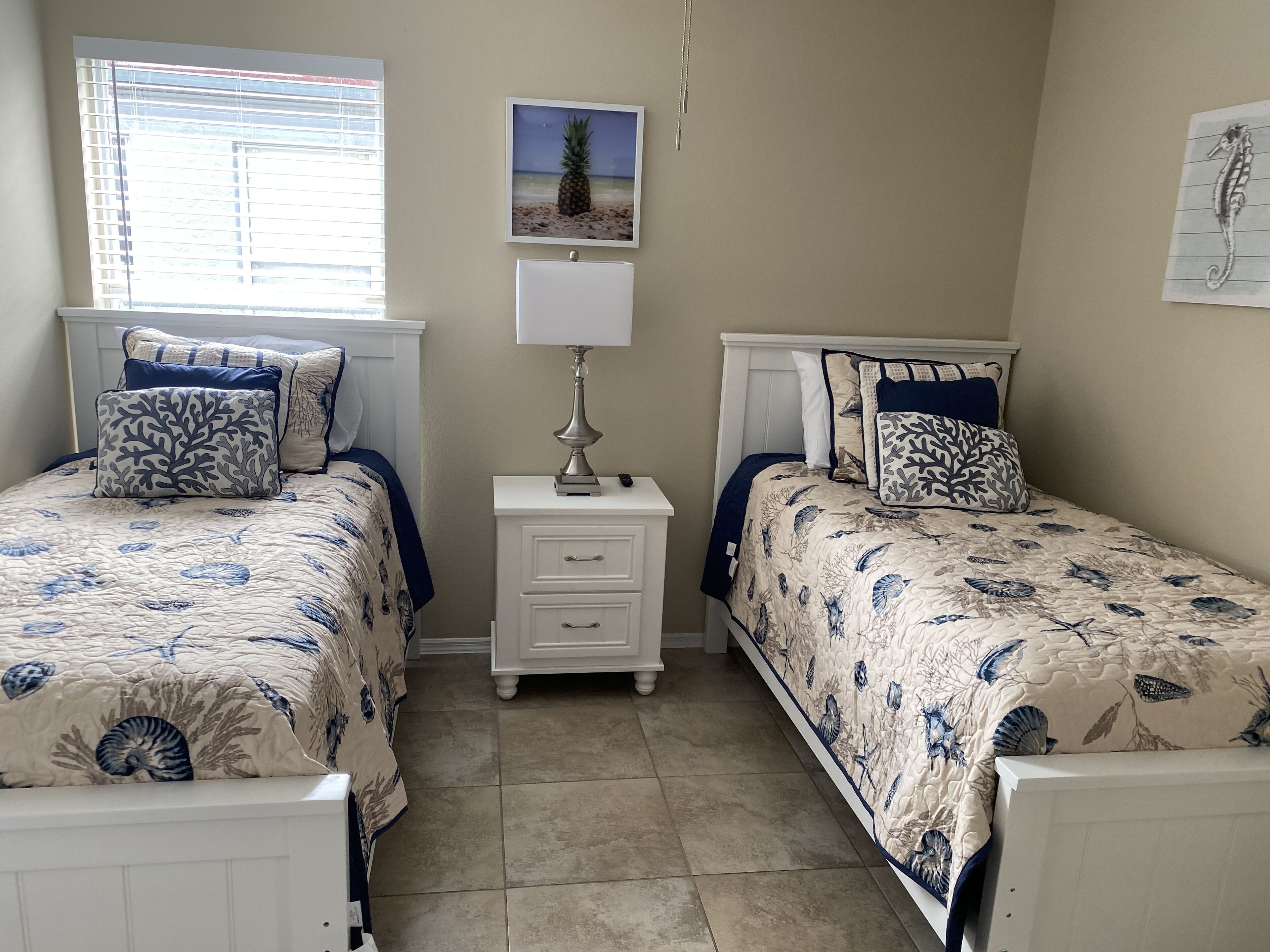 A bedroom with two single beds, a nightstand, a lamp, and a framed picture on the wall.