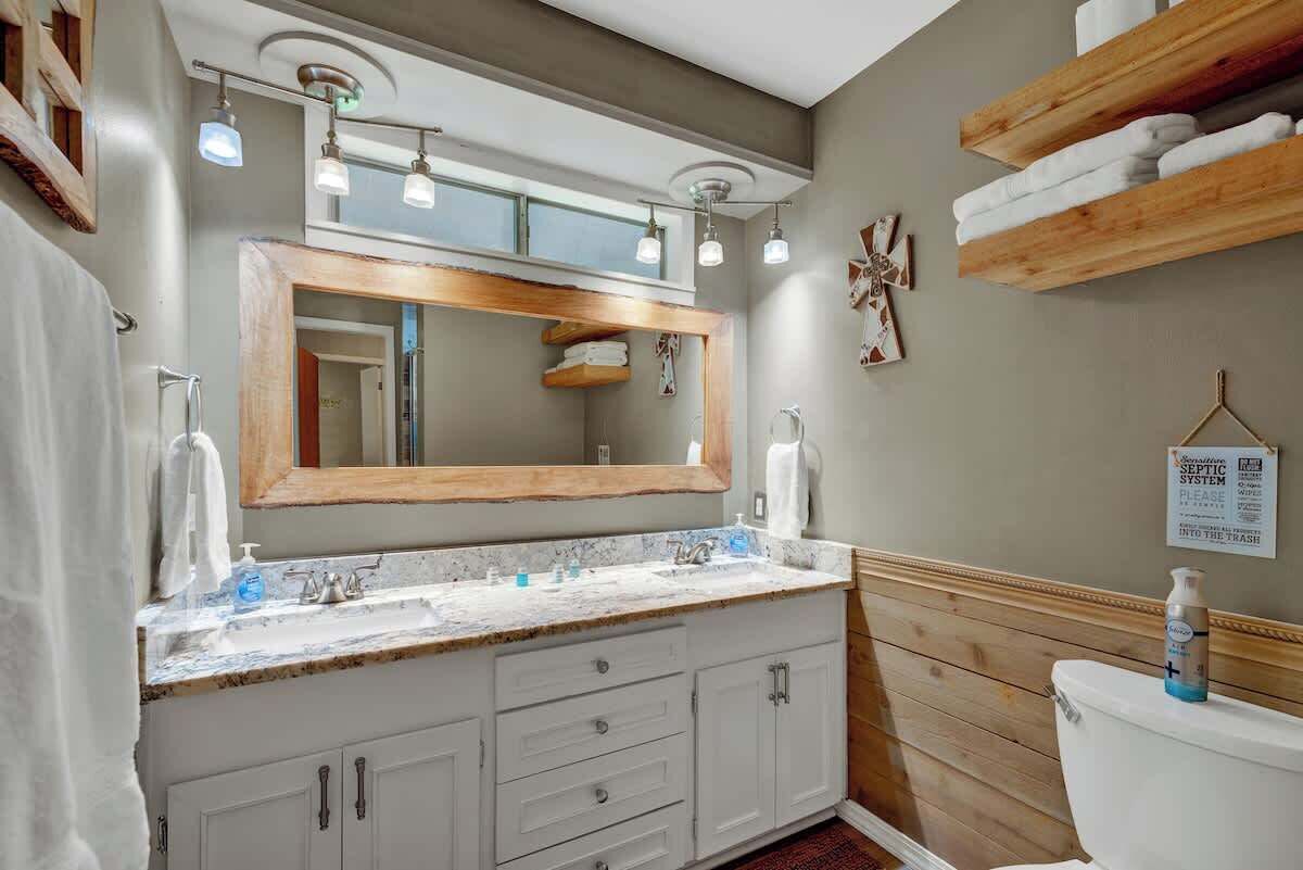 Un baño con tocador de madera, un espejo grande y un inodoro.