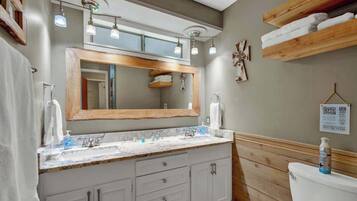 Un baño con tocador de madera, un espejo grande y un inodoro.