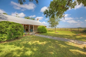 A house with a metal roof, a stone pathway leading to the entrance, and a fenced yard.