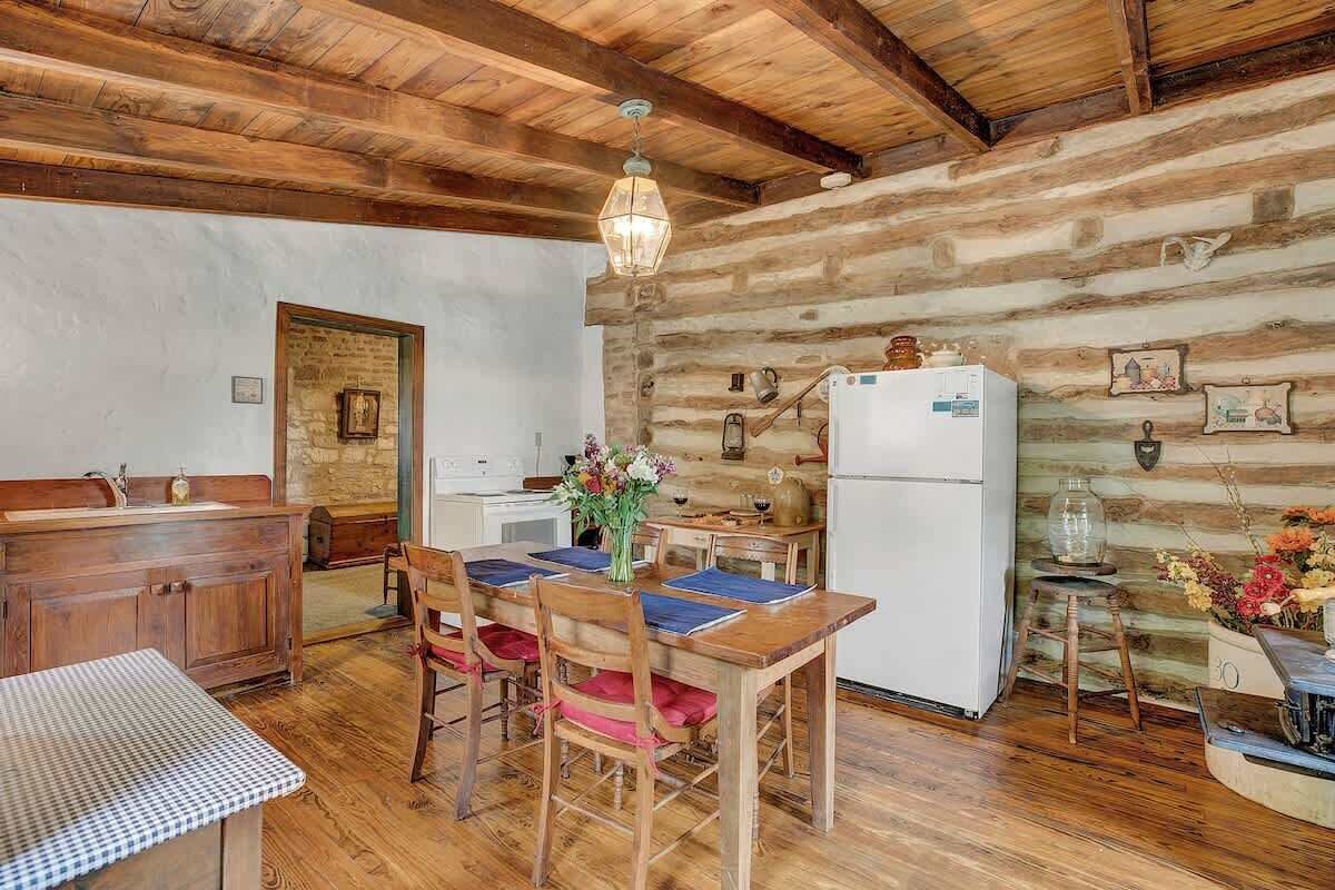 Una cocina rústica con paredes de madera, una mesa de comedor de madera y un refrigerador blanco.
