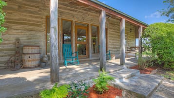 Relax on the covered porch with a comfortable bench and two chairs, surrounded by a serene garden.
