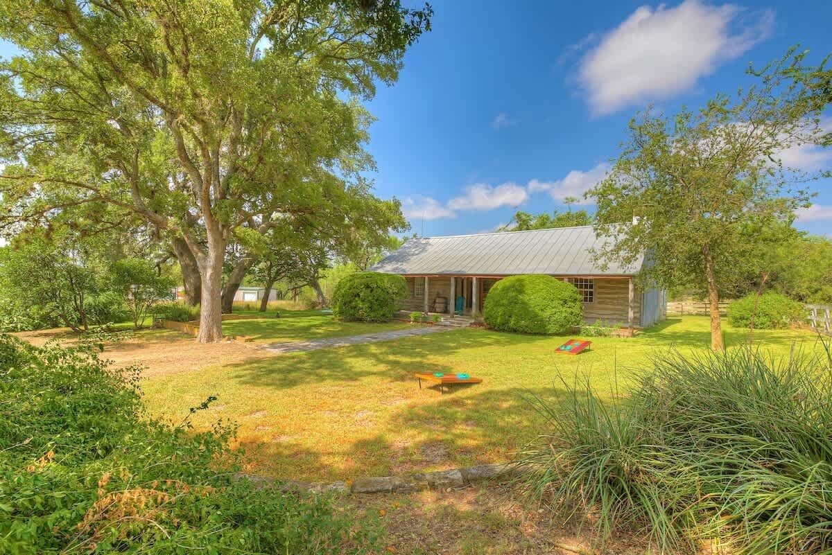 A house with a metal roof, surrounded by a well-maintained lawn and trees.