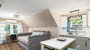 Un dormitorio pequeño con cama, escritorio y kitchenette.