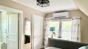 Un dormitorio con cama, mesita de noche, lámpara y ventana con cortinas.