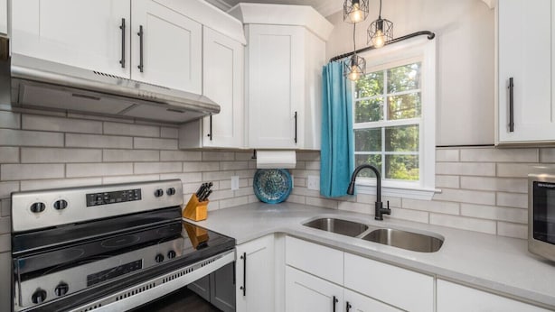 A kitchen with white cabinets, a stainless steel sink, and a double oven.