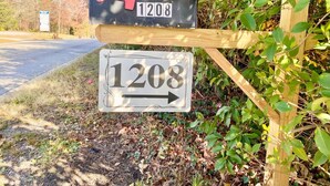 A house number sign with the number 1208, mounted on a wooden post.