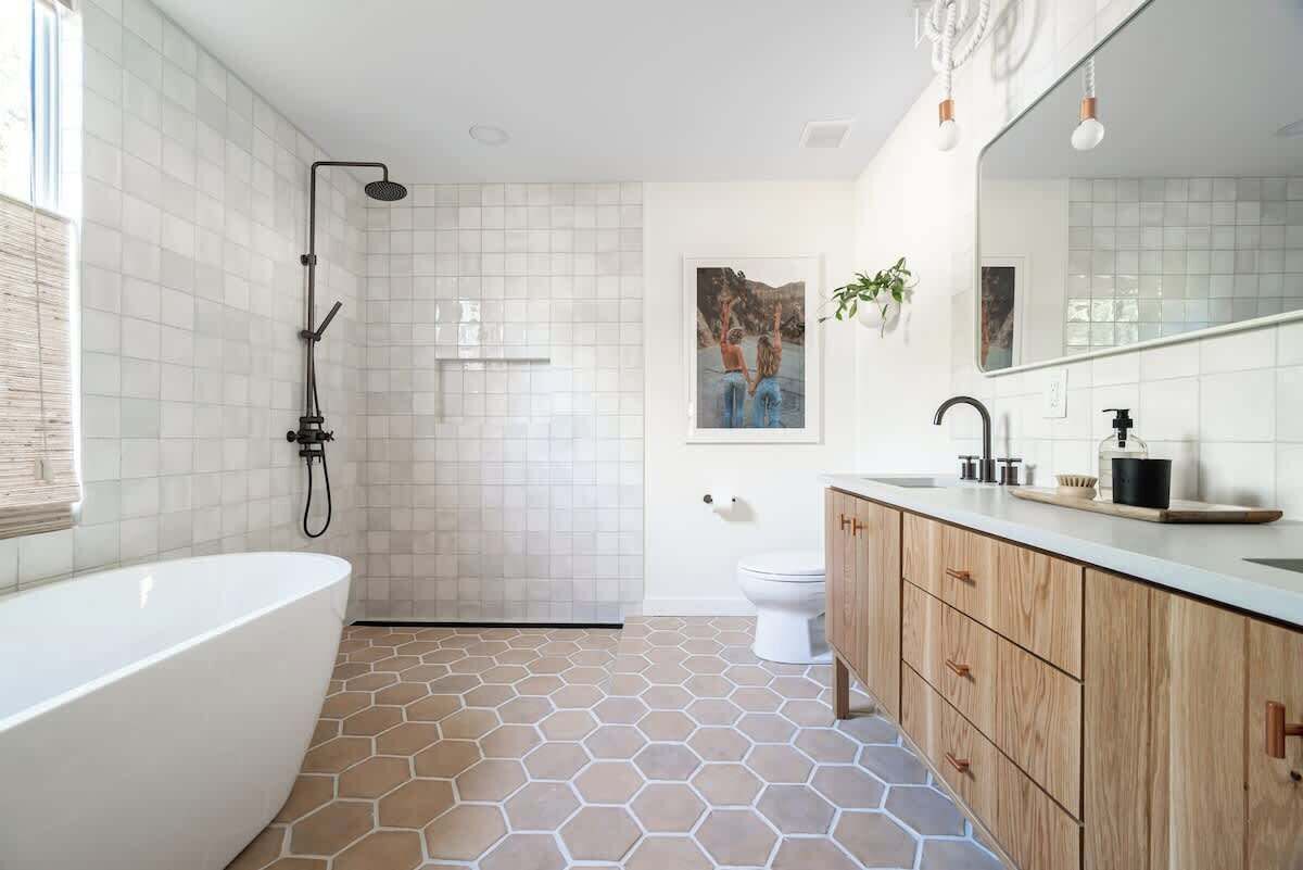 Une salle de bain moderne comprenant une baignoire sur pieds, une douche, des toilettes et un meuble-lavabo avec un miroir.