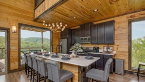 A modern kitchen with a central island, dark cabinets, and a view of the outdoors. - Peace Giver (Gatlinburg)
