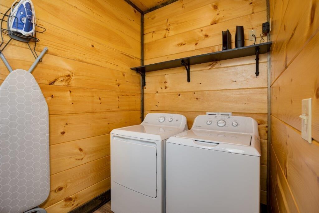 Une petite buanderie avec deux machines à laver blanches, un étendoir et une étagère contenant des produits de nettoyage.