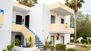 Un bâtiment à deux étages avec un escalier bleu, un petit jardin et un palmier.