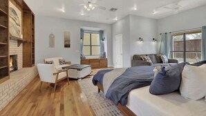 Um quarto espaçoso com uma cama grande, um sofá, uma escrivaninha e uma lareira.