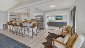 Cozinha moderna com área de bar, banquetas e mesa de jantar.