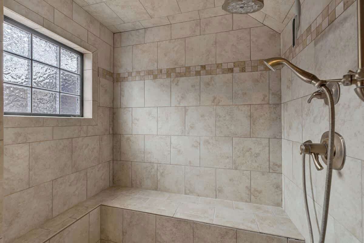 A shower area with a window, tiled walls, and a showerhead.