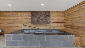 Uma área de spa com uma banheira de pedra quente e paredes revestidas de madeira.