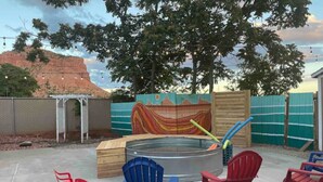 En trädgård med en bubbelpool, Adirondack-stolar och ett trädäck.