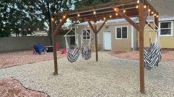 A covered outdoor area with a pergola, string lights, and two hammocks.