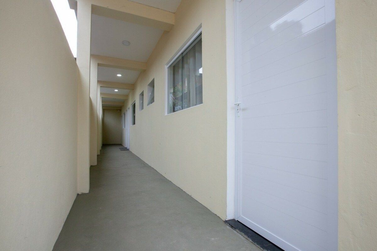 Un corridoio con una porta bianca a destra, una finestra a sinistra e un soffitto con illuminazione a incasso.