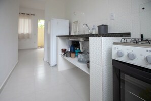 Een keuken met een witte koelkast, een fornuis en een aanrecht met diverse keukenspullen.